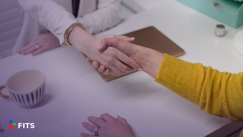 Two people shaking hands across a desk